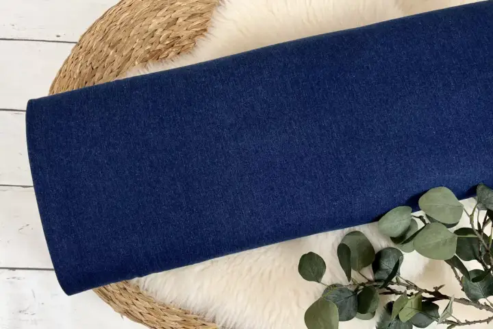 Dunkelblauer Denim-Stoff, aus dem Jeans gemacht sind, liegt auf einem Schaffell.