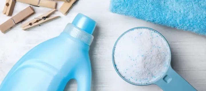 Detersivo in polvere in un misurino accanto a una bottiglia di detersivo liquido. Qual è meglio detersivo in polvere o liquido?
