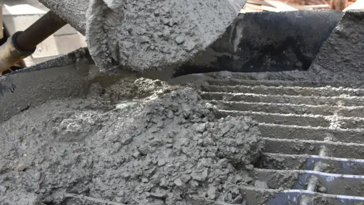 Świeży beton z kruszywem, idealny jako jaki beton pod obrzeża, wylewany na ruszt.