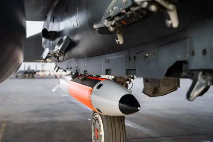 Podwieszona pod samolotem bomba lotnicza, pomarańczowo-szara, gotowa do akcji. To jest właśnie power bomb 4t, co daje jej moc.