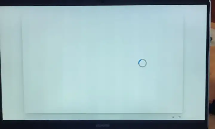 Jasny, biały ekran laptopa z niebieskim kółkiem ładowania pośrodku. Czekam na zakończenie procesu.