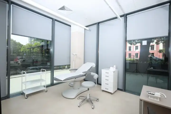 Gabinet dermatologii estetycznej z fotelem zabiegowym, szafką i wózkiem.