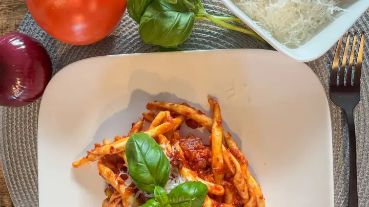 Makaron z sosem nduja, pomidorami, cebulą i bazylią. Pyszne danie, które wyjaśnia, nduja co to jest – pikantna, smarowna włoska kiełbasa.