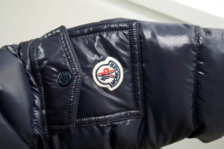 Granatowa, błyszcząca kurtka z naszywką Moncler. Czy to właśnie ta firma, o którą pytasz?
