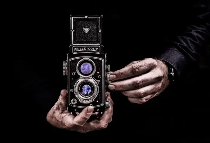 Dłonie trzymające aparat Rolleicord, uchwycone w kadrze zgodnym ze złotym podziałem.