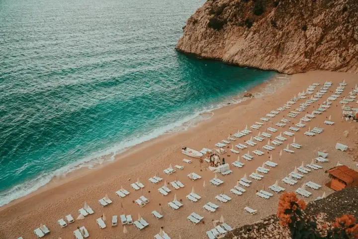 Piękna plaża z rzędami leżaków i turkusową wodą. Idealne miejsce, by zastanowić się, gdzie do Turcji na wakacje.