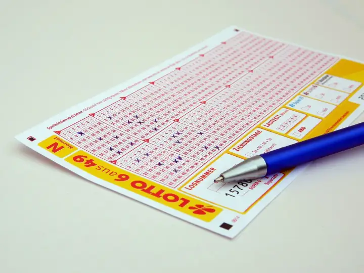 Kupon do gry Lotto z zaznaczonymi liczbami i długopisem. Zastanawiasz się, jak zablokować konto na stronie Lotto samowykluczenie na stałe?