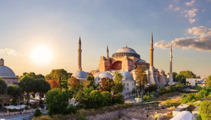 Majestatyczny meczet Hagia Sophia w Stambule, z minaretami i kopułami, oświetlony zachodzącym słońcem.