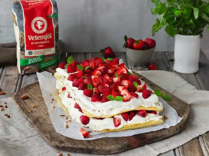 En vacker Pinocchiotårta med grädde och bär, perfekt för sommaren. Receptet kan hittas online.