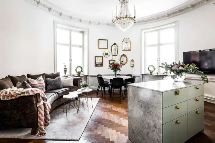 Ett vardagsrum med mörk soffa, marmorö, och en matplats. Massor av speglar på väggen ger inredning inspiration.
