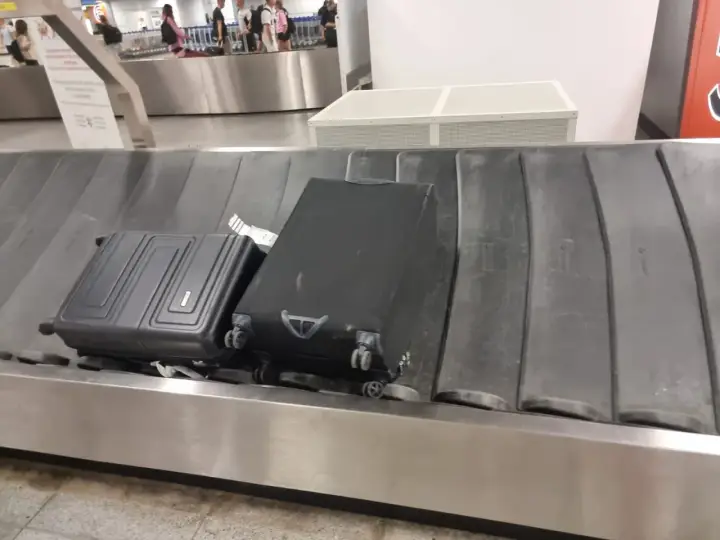 Dwa bagaże, w tym czarna walizka, czekają na odbiór na taśmie bagażowej. To typowy widok po przylocie liniami Ryanair.