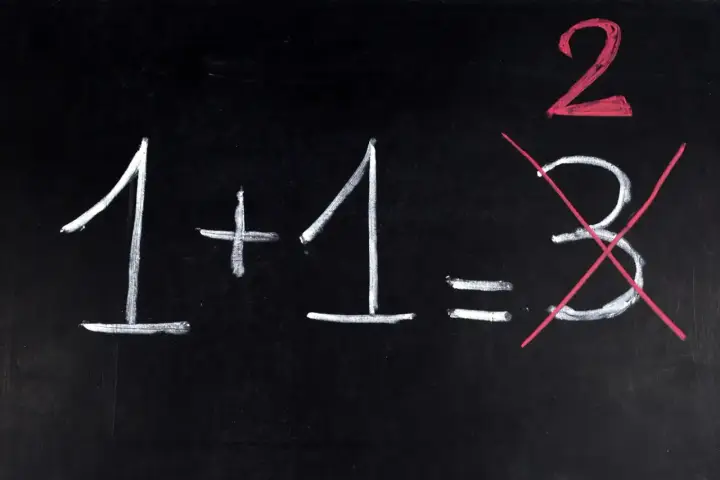Na czarnej tablicy napisano kredą: 1+1=2. Liczba 3 jest przekreślona, jakby to był trudny egzamin dojrzałości.