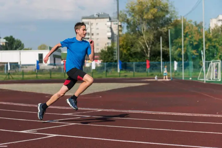 Młody biegacz na bieżni podczas zajęć sportowych dla młodzieży.