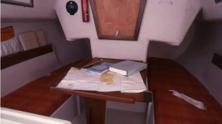 Vue du premier 22 intérieur d'un voilier, avec une carte marine, des livres et un compas.