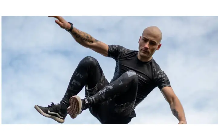 Mężczyzna w ruchu, jakby ćwiczył hiit. Co to za trening? Dynamiczne skoki i akrobacje na tle nieba.