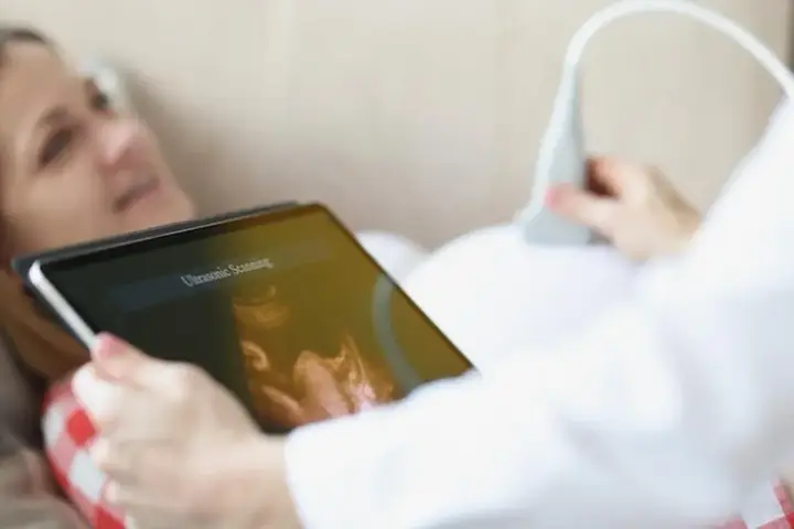 Kobieta na tablecie widzi obraz z USG. To badanie ultrasonograficzne, które pokazuje rozwój dziecka.
