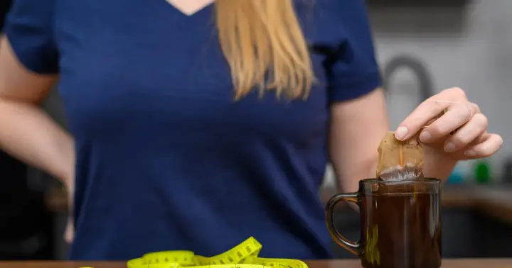Kobieta zanurza torebkę herbaty w kubku, obok leży miarka. Czy nerki można wygrzewać?