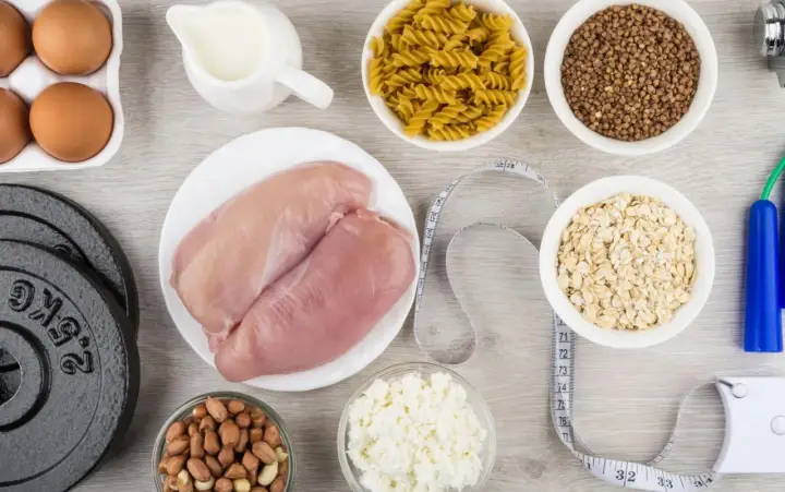 Składniki na dietę na masę mięśniową: kurczak, jajka, mleko, płatki owsiane, makaron, kasza gryczana, orzeszki ziemne, twaróg, hantle i skakanka.