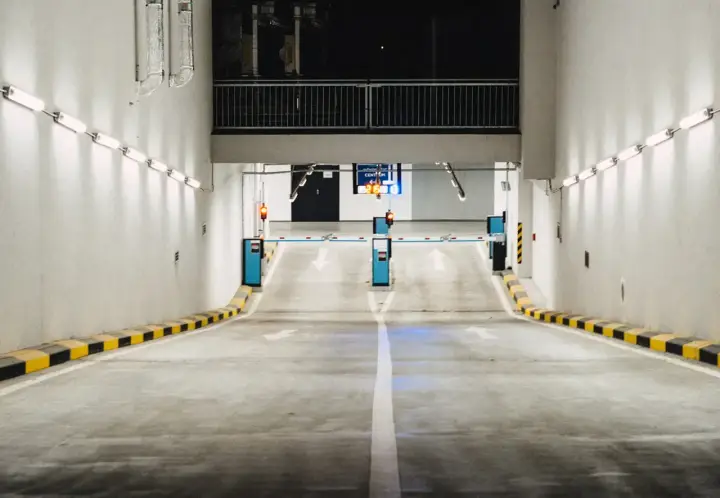 Einfahrt in eine Tiefgarage mit Schranken und Pfeilen, die den Weg weisen. Effizientes Parkraummanagement sorgt für Ordnung.