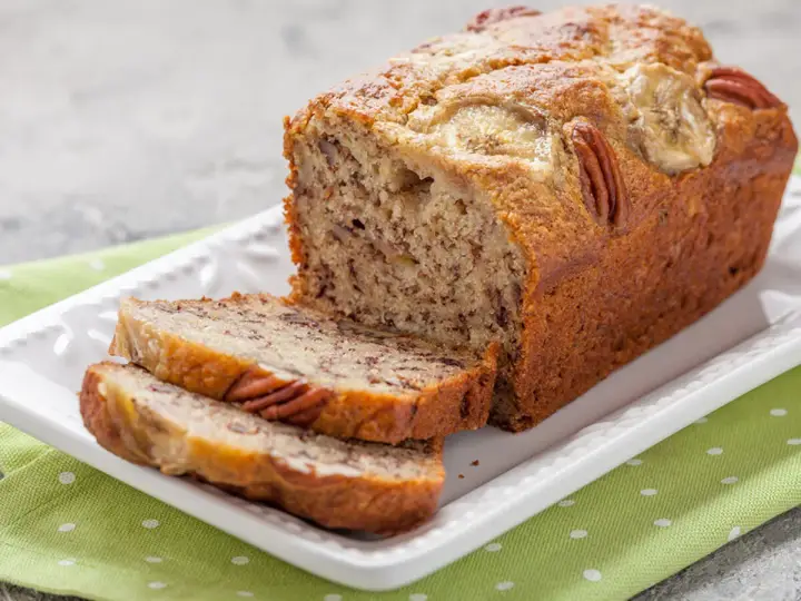 Chlebek bananowy Ani gotuje się wspaniale, z orzechami pekan i plasterkami banana na wierzchu.