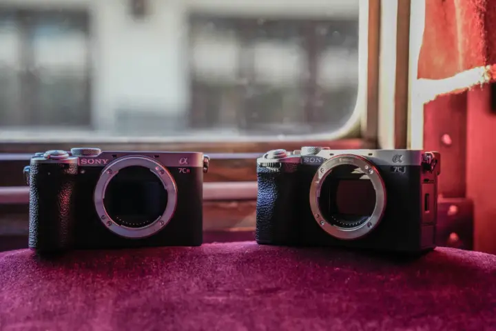 Dwa aparaty Sony Alpha, jeden a7c i drugi a7CR, leżą obok siebie na aksamitnym materiale.