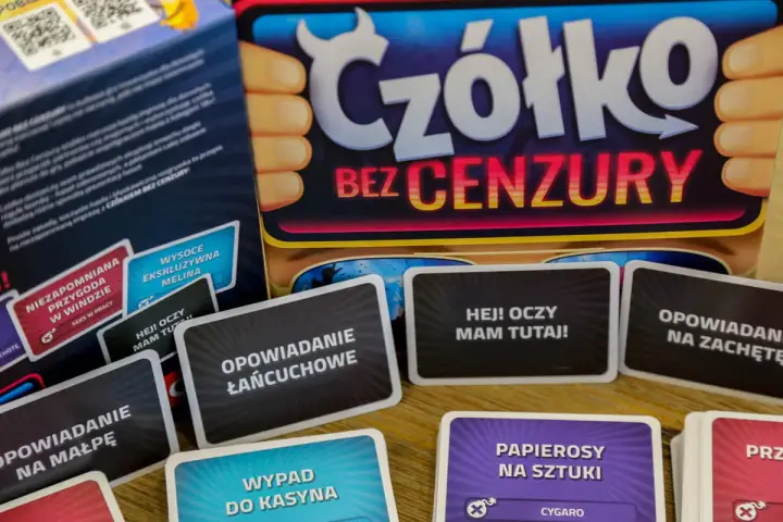 Karty do gry "Czółko bez cenzury" leżą na stole. Widać napisy: "Opowiadanie łańcuchowe", "Hej! Oczy mam tutaj!", "Opowiadanie na małpę", "Wypad do kasyna".