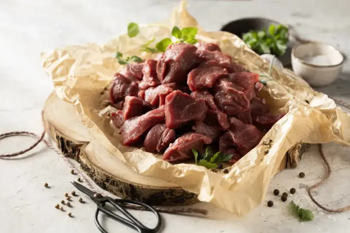 Pokrojone w kostkę mięso na gulasz z dzika, ułożone na papierze, gotowe do przyrządzenia.