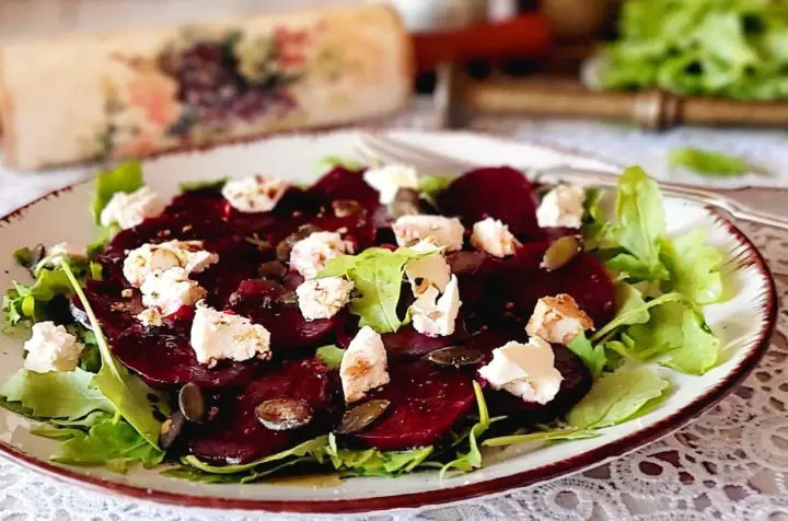 Pyszne carpaccio z buraka z serem feta, rukolą i pestkami dyni na talerzu.