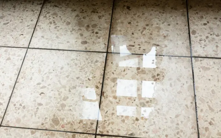 Eau sur le sol d'une maison, reflétant la lumière. L'isolation du sol est compromise.