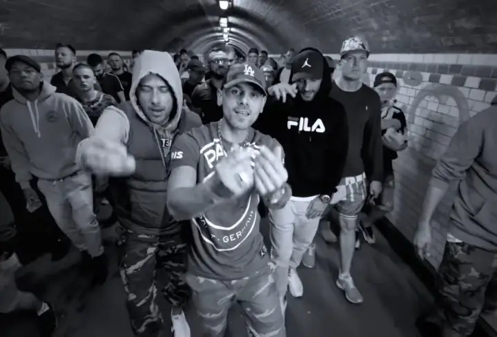 Gibbs, daj tylko czas tekst. Grupa mężczyzn w tunelu, jeden z nich w bluzie Fila, inny w bluzie z kapturem.