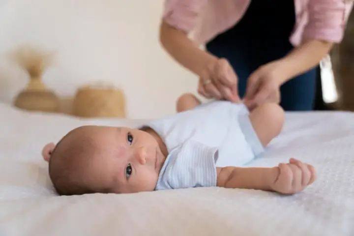 Malutkie dziecko leży na białym kocyku. Mama przygotowuje się do szczepienia RSV w ciąży, by chronić maluszka.
