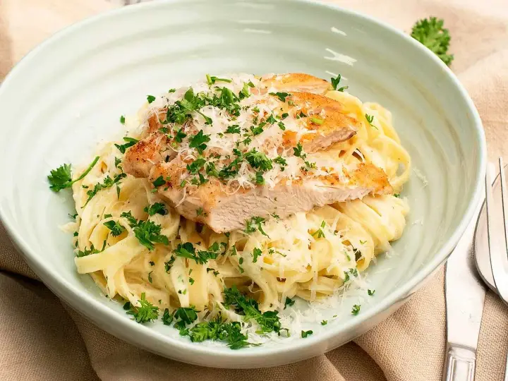En krämig kyckling alfredo med tagliatelle, toppad med grillad kyckling, parmesan och färsk persilja. Ett perfekt recept för en snabb middag.