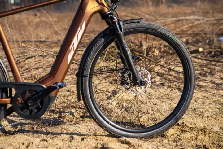 Vorderreifen und Federgabel eines braunen KTM Macina Style E-Bikes. Der Unterschied zwischen dem KTM Macina Style 720 und 730 liegt in den Details.