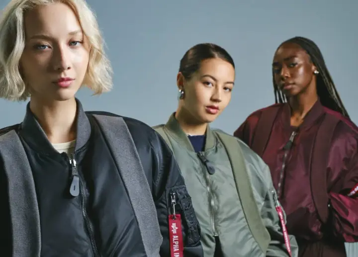 Trzy kobiety w kurtkach bomberkach Alpha Industries. To znana marka odzieży lotniczej.
