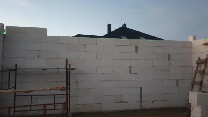 Budowa domu z bloczków, zielona linia laserowa wyznacza poziom. To dobry pomysł na krzywe ściany, jeśli chcesz uzyskać ciekawy efekt architektoniczny.