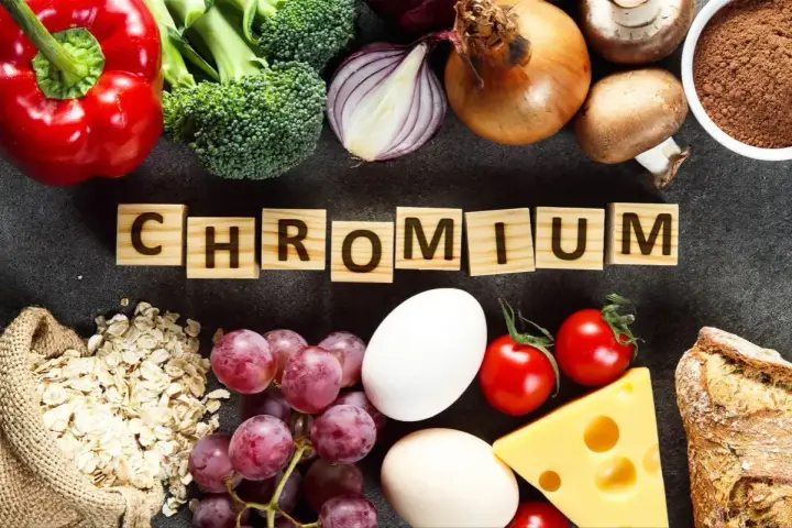 Słowa "CHROM" na drewnianych klockach otoczone przez produkty bogate w ten pierwiastek: papryka, brokuły, cebula, jajka, winogrona, owies, ser, pomidory, grzyby, chleb i proszek.