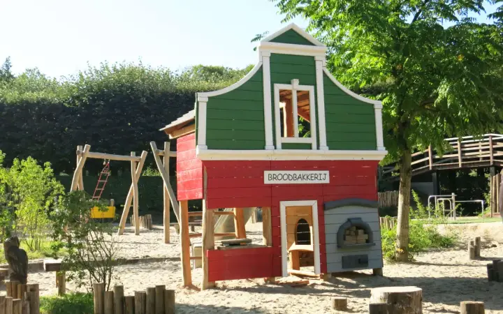 Parque infantil en Holanda con casita de panadería, columpios y tobogán. Ideal para que los niños jueguen y se diviertan.
