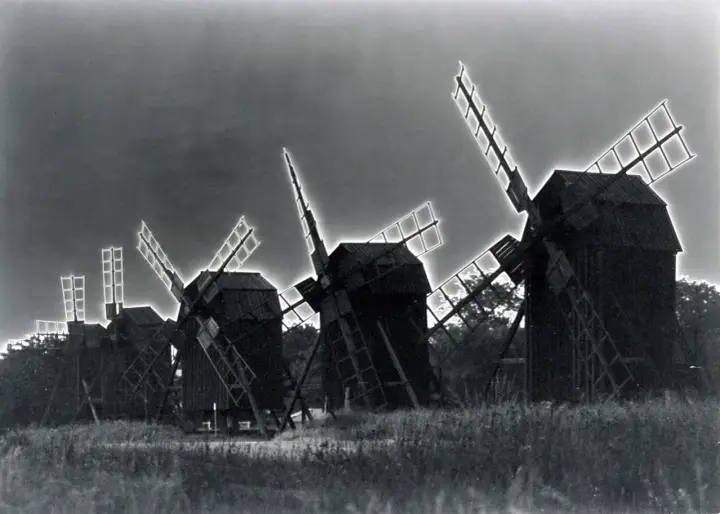 Mulini a vento in un campo, con un effetto di solarizzazione man ray che illumina le pale.