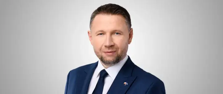 Mężczyzna w granatowym garniturze, z krótkimi włosami i zarostem, to minister spraw wewnętrznych.