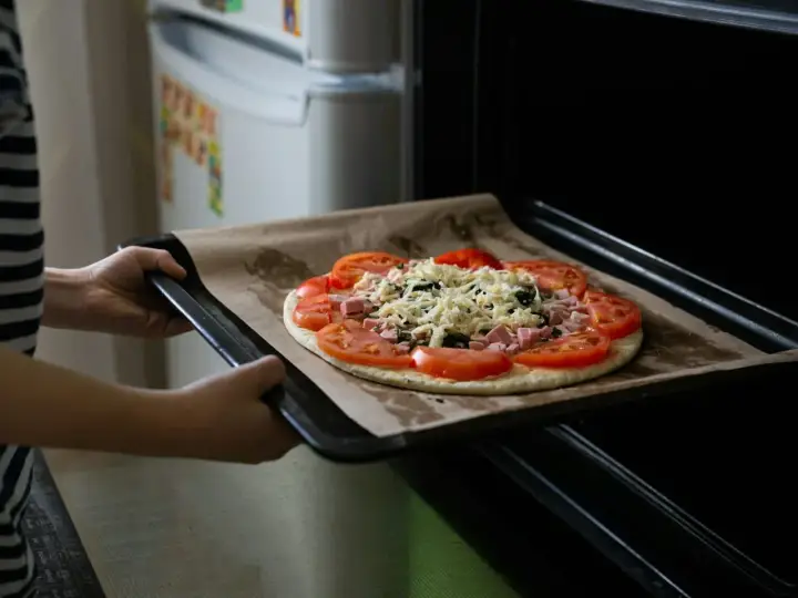 Wkładanie pizzy do piekarnika. Dzięki termoobiegowi ciasto będzie chrupiące, a ser idealnie roztopiony.