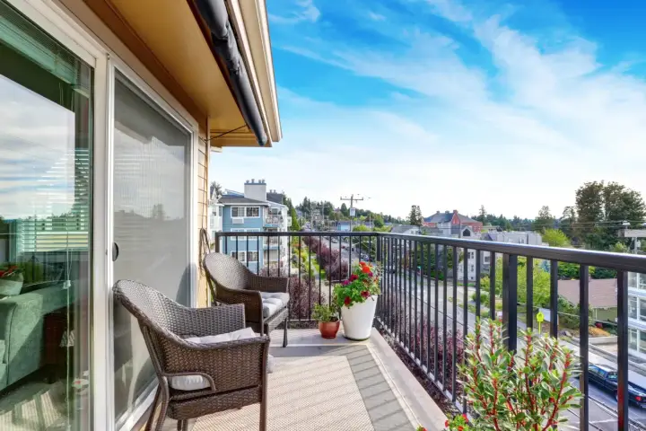 Wygodny balkon z rattanowymi meblami i kwiatami. Inspiracje na płytki na balkon.