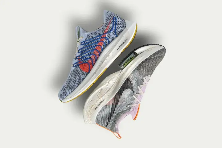 Dwa buty sportowe Nike, jeden niebieski z czerwonymi akcentami, drugi szaro-fioletowy. To przyszłość biegania z Nike Move to Zero.