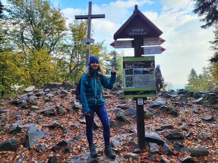 Kobieta na szczycie Łysicy, 614 m n.p.m., przy drogowskazie szlak łysica - kakonin. Jesień w pełni, liście na ziemi.