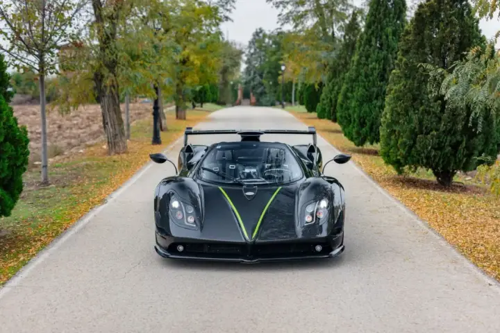 Czarny Pagani Zonda z zielonym akcentem na masce, zaparkowany na alei. Jego cena jest astronomiczna.
