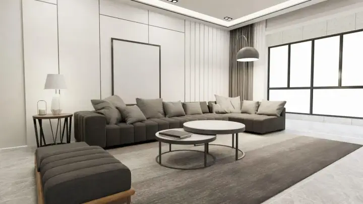Nowoczesny salon z szarą sofą, dwoma stolikami kawowymi i dywanem. Wnętrze emanuje **quiet luxury**, gdzie każdy element jest dopracowany w subtelny sposób.
