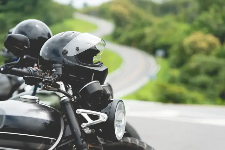 Gotowe na przygodę? Zastanawiasz się nad prawem jazdy na motor i wiekiem? Dwa kaski czekają na motocyklistów na krętej drodze.