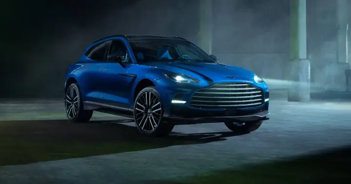 Niebieski Aston Martin DBX 707 lśni w mrocznym, industrialnym otoczeniu.