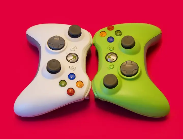 Biały i zielony kontroler Xbox 360 obok siebie. Idealne do gier strategicznych w czasie rzeczywistym, wymagających szybkiego myślenia i precyzji.