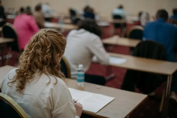 Uczestnicy piszą egzamin z angielskiego. Zastanawiają się, ile trwa egzamin z angielskiego, skupieni na zadaniach.