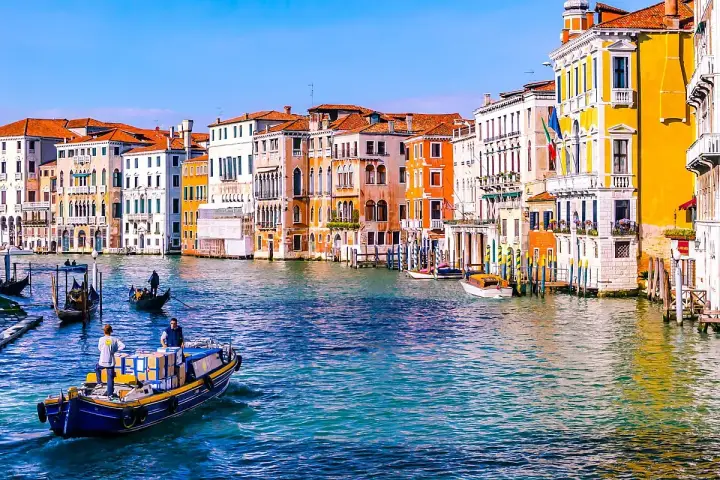 Gondole e vaporetti sul Canal Grande, un assaggio di cosa vedere a Venezia in due giorni. Palazzi colorati e acqua scintillante.